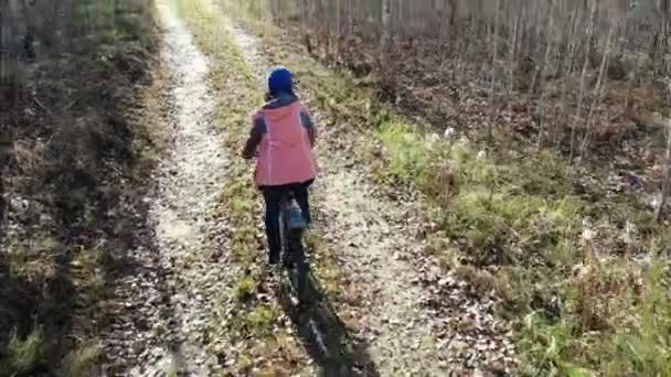 Женщина с избыточным весом на велосипеде в солнечном осеннем лесу, воздушный кадр — стоковое видео