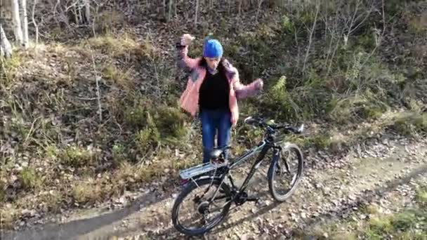 Funny woman bicycle rider dancing outdoors in autumn forest, happiness success relax winner, aerial — Stock Video