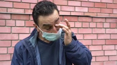 Maskeli bir adam kaşınıyor gözlerini kaşındırıyor, hasta, alerji, korona virüsü belirtileri.