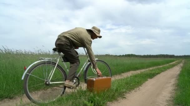 Man op bicyle grijpen koffer met schatten die hij vond op het platteland weg, concept te vinden — Stockvideo