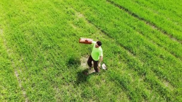 Man ensam män snurrar i ett grönt fält, håller resväska i en hand, rolig resekoncept, retro — Stockvideo