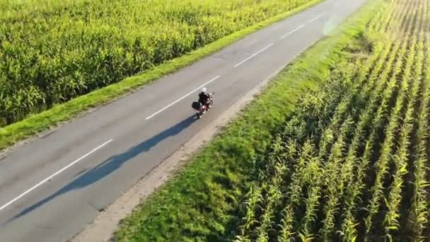 在日落时骑摩托车经过乡间公路，从无人驾驶飞机上拍摄美丽的冒险旅行镜头，顶部 — 图库视频影像