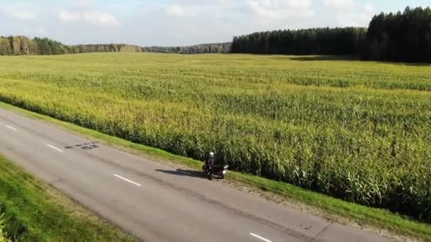 Mengendarai sepeda motor oleh jalan negara pada saat matahari terbenam, indah petualangan cuplikan diambil dari drone, atas — Stok Video