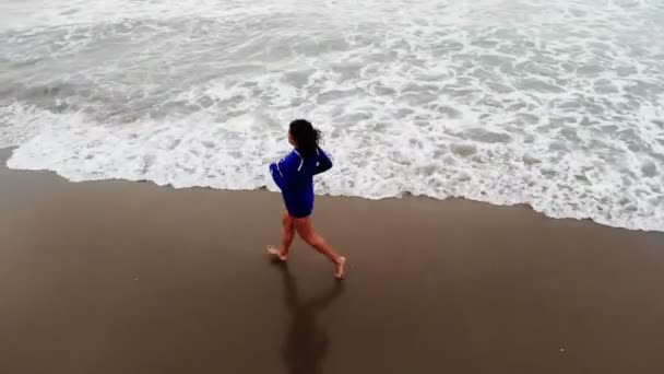 Vrouw in blauwe jurk loopt door het water op zandstrand aan de kust bij zonsondergang, inspirerende — Stockvideo