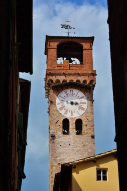 Lucca Ortaçağ 'Torre delle cevheri' (Saat Kulesi), şehrin tarihi merkezi bulutlu gökyüzü ile dar bir sokakta görüldü