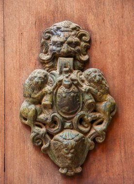 İki aslan, korkunç yüz ve ahşap bir kapı üzerinde pas arasında amblemi ile çok eski kapı tokmağı