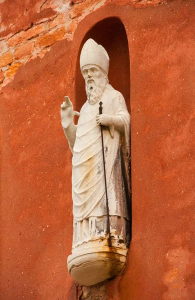 Blessing Pope, Bishop or Saint with cane, an ancient statue on a wall in the historic center of Venice