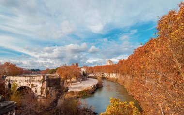 Sonbahar ve yeşillik Roma'da. Kırmızı ve sarı yaprakları Tiber Adası iki eski köprü ve şehir tarihi merkezinde güzel gökyüzü