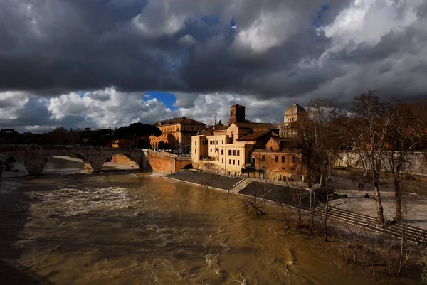 stock image Winter in Rome. River is swollen along Tiber Island embankments under stormy clouds