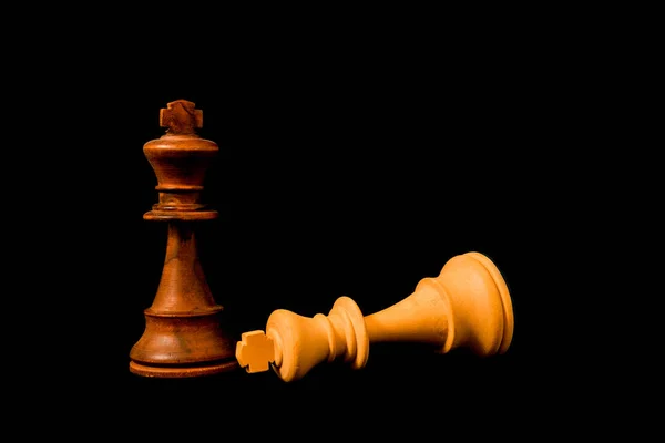 White King surreder to Black King at the end of the game. Two strandard chess wooden pieces on black background