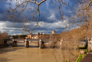 Kış Roma'da Tiber Nehri'nin, boyunca fırtınalı bulutlar çıplak dal ağaçların arasından görüntülemek