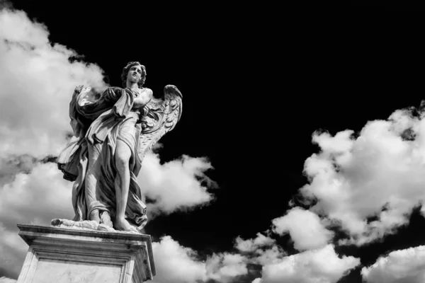 天の雲とイエス キリストの情熱の衣服とダイスを保持天使像 ローマの中心部にあるサンタンジェロ橋の上にある17世紀のバロック様式の傑作 コピースペースのある黒と白 — ストック写真