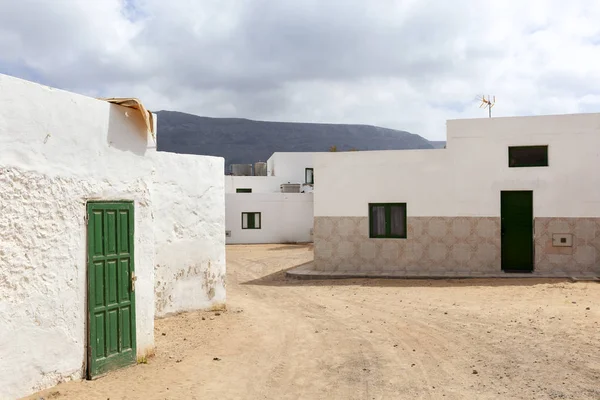 Empty street with sand and white houses in Caleta de Sebo on the