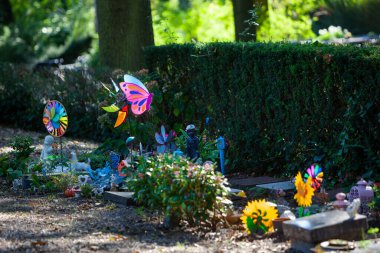 Tombstones and colorful toys on a part of the cemetery for children in Rotterdam in the Netherlands clipart