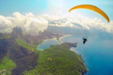 Yamaç paraşütü gökyüzünde. Yamaçparaşütü tandem denizin masmavi bir deniz ve dağ üzerinde parlak güneşli bir günde uçan. Yamaçparaşütü ve Blue Lagoon Ölüdeniz, Türkiye'de hava görünümünü. Aşırı spor. Manzara