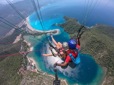 Yamaç paraşütü gökyüzünde. Yamaçparaşütü tandem denizin masmavi bir deniz ve dağ üzerinde parlak güneşli bir günde uçan. Yamaçparaşütü ve Blue Lagoon Ölüdeniz, Türkiye'de hava görünümünü. Aşırı spor. Manzara