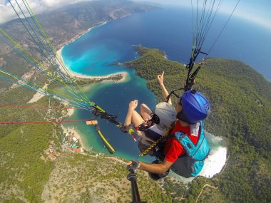 Yamaç paraşütü gökyüzünde. Yamaçparaşütü tandem denizin masmavi bir deniz ve dağ üzerinde parlak güneşli bir günde uçan. Yamaçparaşütü ve Blue Lagoon Ölüdeniz, Türkiye'de hava görünümünü. Aşırı spor. Manzara