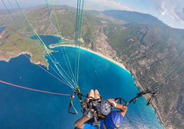 Yamaç paraşütü gökyüzünde. Yamaçparaşütü tandem denizin masmavi bir deniz ve dağ üzerinde parlak güneşli bir günde uçan. Yamaçparaşütü ve Blue Lagoon Ölüdeniz, Türkiye'de hava görünümünü. Aşırı spor. Manzara