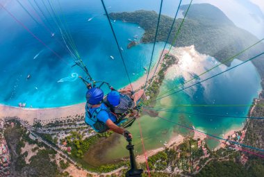Yamaç paraşütü gökyüzünde. Yamaçparaşütü tandem denizin masmavi bir deniz ve dağ üzerinde parlak güneşli bir günde uçan. Yamaçparaşütü ve Blue Lagoon Ölüdeniz, Türkiye'de hava görünümünü. Aşırı spor. Manzara