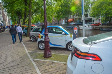 Amsterdam, Hollanda, 15 Ağustos 2014: Bir elektrikli araba Hollanda Amsterdam yükleme enerjisini kanalda nehir Amstel eski Avrupa şehri bahar manzara evleri