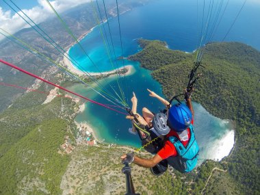 Yamaç paraşütü gökyüzünde. Yamaçparaşütü tandem denizin masmavi bir deniz ve dağ üzerinde parlak güneşli bir günde uçan. Yamaçparaşütü ve Blue Lagoon Ölüdeniz, Türkiye'de hava görünümünü. Aşırı spor. Manzara