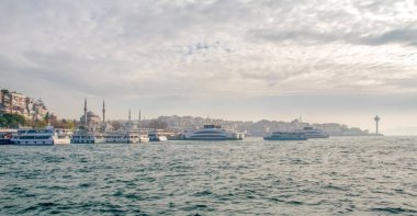 İstanbul, Türkiye 03 Nisan 2019: Türkiye'de Müslüman mimarisi ve su taşımacılığı - İstanbul Boğazı'nda deniz yolculuğundan gelen turistik manzaralar. Gün batımında İstanbul Şehir Manzarası - eski cami ve türk vapurları, Haliç manzarası.