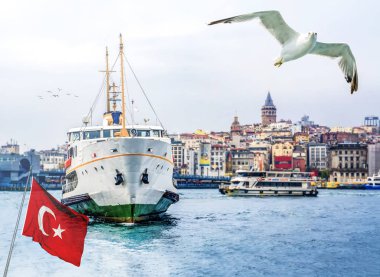 İstanbul Manzara - Galata köprüsü ve Beyoğlu ilçesinin rıhtım yakınındaki eski kentin şehir silueti. Haliç üzerinde yolcu gemileri, Türk bayrağı ve uçan kuşlar ile sahil manzarası