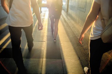 Beyaz bir parıltı karşı karanlık bir tünelde yürüyen insan siluetleri