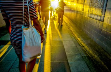 Beyaz bir parıltı karşı karanlık bir tünelde yürüyen insan siluetleri