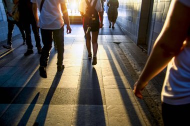 Beyaz bir parıltı karşı karanlık bir tünelde yürüyen insan siluetleri