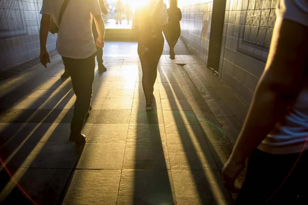 Beyaz bir parıltı karşı karanlık bir tünelde yürüyen insan siluetleri
