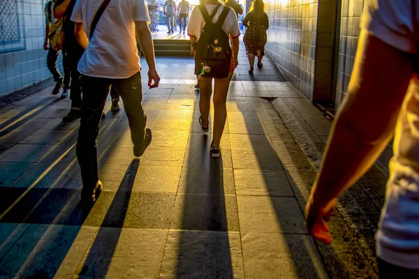 Silhouettes of people walking in a dark tunnel against a white glow