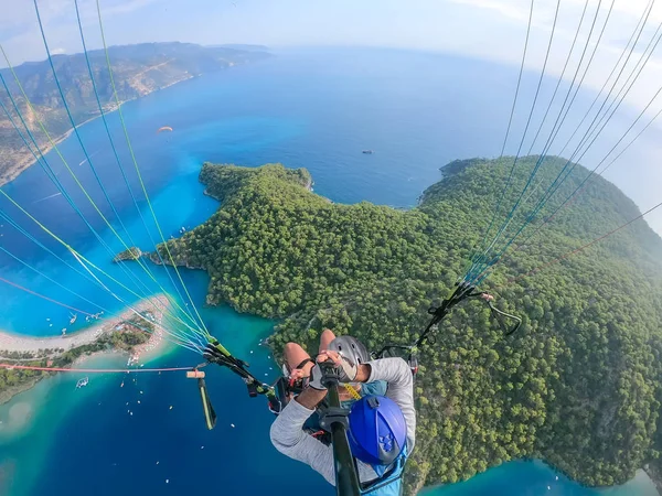 Extreme sport. Landscape . Paragliding in the sky. Paraglider tandem flying over the sea with blue water and mountains in bright sunny day. Aerial view of paraglider and Blue Lagoon in Oludeniz, Turkey.