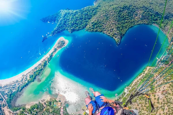 Extreme sport. Landscape . Paragliding in the sky. Paraglider tandem flying over the sea with blue water and mountains in bright sunny day. Aerial view of paraglider and Blue Lagoon in Oludeniz, Turkey.