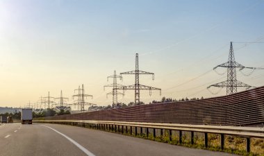 Yüksek gerilim elektrik direkleri ve iletim güç hatları mavi gökyüzü arka plan üzerinde.