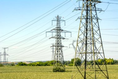 Yüksek gerilim elektrik direkleri ve iletim güç hatları mavi gökyüzü arka plan üzerinde.