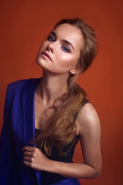 Genç çekici kadın modeli , mor takım elbise giyiyor , stüdyoda poz. Turuncu arka plan.