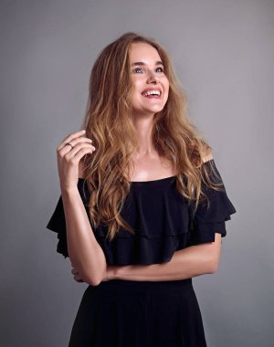 Genç çekici kadın modeli, uzun saçlı, siyah takım elbise giyen, stüdyoda poz. Gri arka plan.