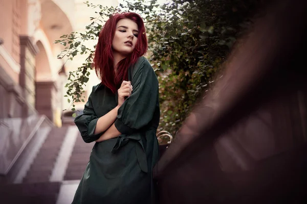 ロマンチックな緑のドレスと赤い髪の若いファッショナブルな女性は 公園の家の近くでポーズ — ストック写真