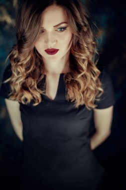 Kahverengi kıvırcık saçlı genç güzel kız portresi, siyah elbise, şık makyaj giymiş. Stüdyo çekimi