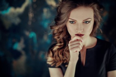 Kahverengi kıvırcık saçlı genç güzel kız portresi, siyah elbise, şık makyaj giymiş. Stüdyo çekimi