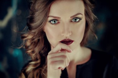 Kahverengi kıvırcık saçlı genç güzel kız portresi, siyah elbise, şık makyaj giymiş. Stüdyo çekimi