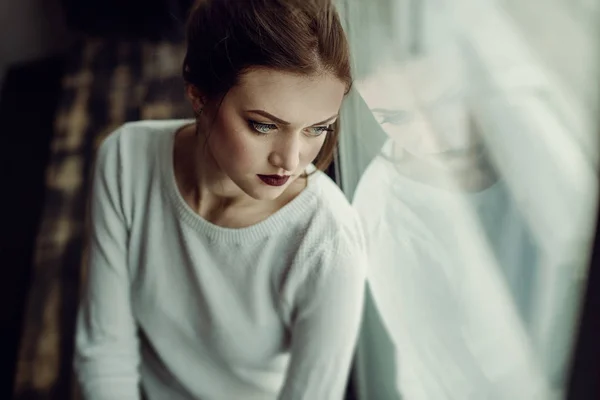 Kahverengi kıvırcık saçlı genç güzel kız portresi, beyaz kazak, şık makyaj giyilen. Stüdyo çekimi