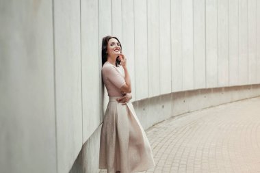 Açık giysiler giyen koyu saçlı güzel orta eged gülümseyen kadın model, yaz günü sokakta poz 