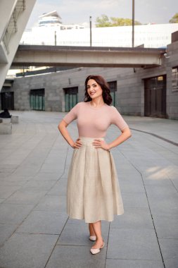 Açık giysiler giyen koyu saçlı güzel orta eged gülümseyen kadın model, yaz günü sokakta poz 