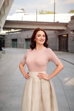 Açık giysiler giyen koyu saçlı güzel orta eged gülümseyen kadın model, yaz günü sokakta poz 