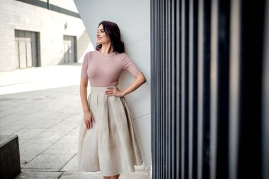 Açık giysiler giyen koyu saçlı güzel orta eged gülümseyen kadın model, yaz günü sokakta poz 