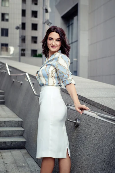 Açık giysiler giyen koyu saçlı güzel orta eged gülümseyen kadın model, yaz günü sokakta poz