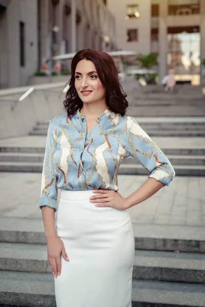 Açık giysiler giyen koyu saçlı güzel orta eged gülümseyen kadın model, yaz günü sokakta poz