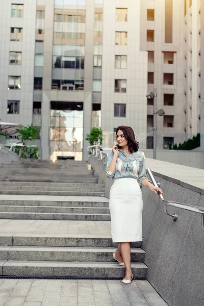 Açık giysiler giyen koyu saçlı güzel orta eged gülümseyen kadın model, yaz günü sokakta poz